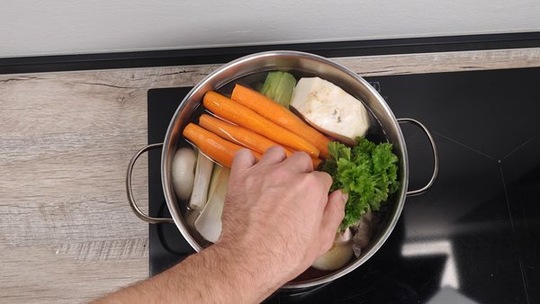 Carrots, leek, celery root and parsley added to a pot of homemade beef soup