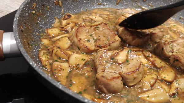 Pork tenderloin with mushroom sauce and creamy polenta on a skillet.