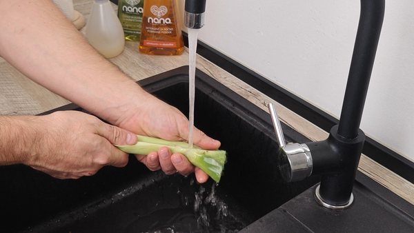 Washing leek under running water while preparing vegetables for beef soup